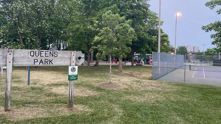 Queen's Park sign with tennis courts and playground in background